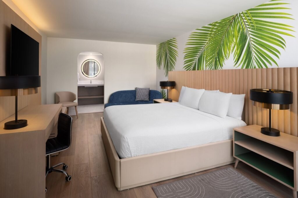 Premium Mini Suite King room at The Harrison Hotel Downtown Hollywood with tropical palm leaf wall mural, king bed, and separate sofa seating area