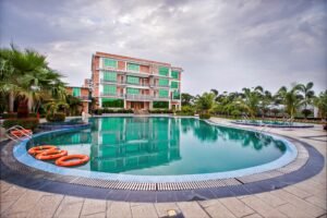 Large swimming pool with lounge floats in front of the main building at Shaira Garden Hotel & Resorts, Narayanganj